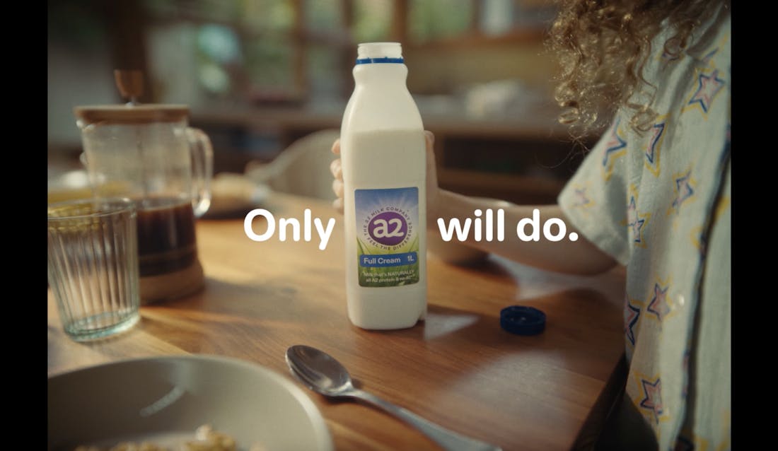 The hand of a girl holding an a2 milk bottle with the caption 'Only a2 Will Do.'