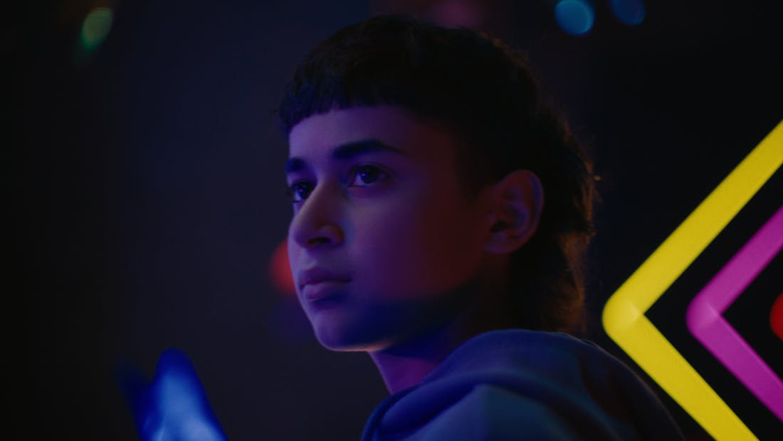 A boy's profile backlit by neon signs