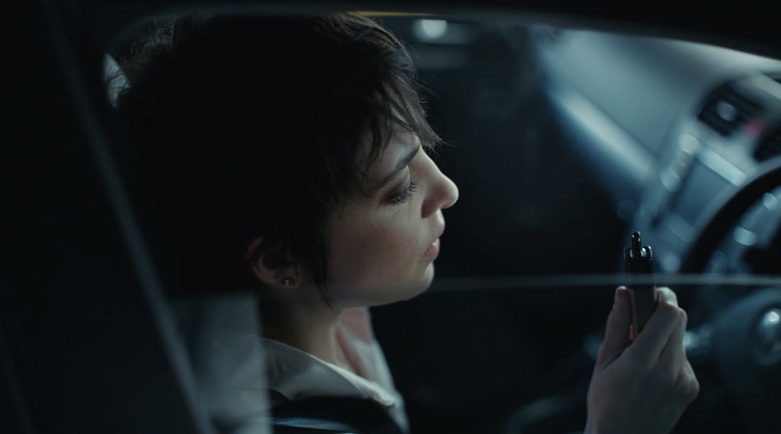 Woman sitting in her car holding a vape.