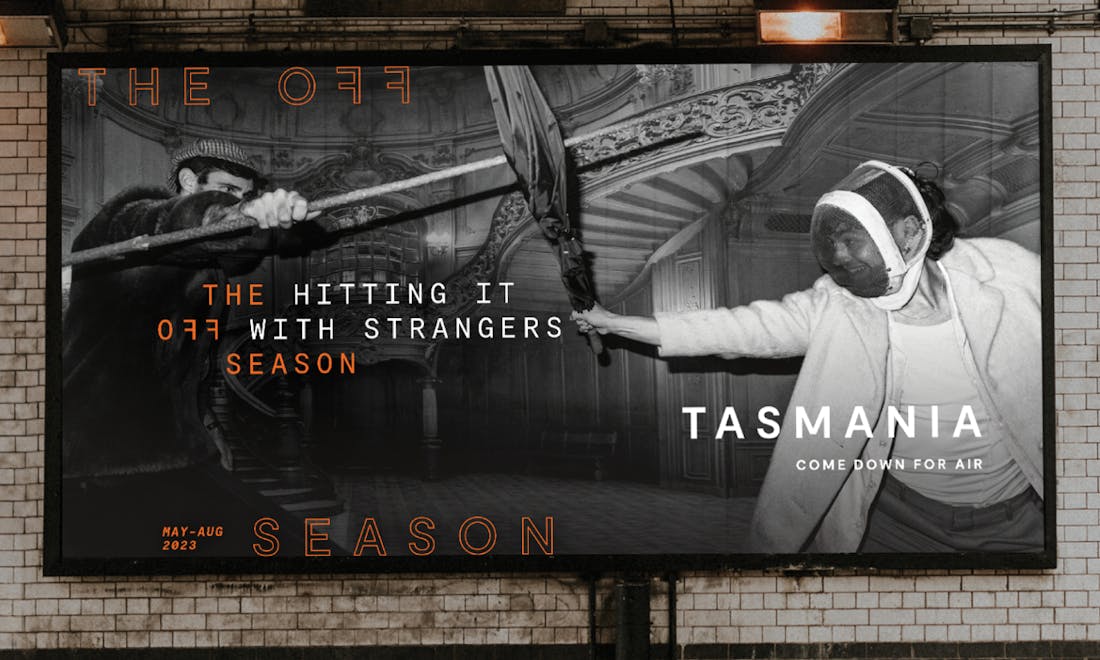 A billboard advertisement for Tourism Tasmania featuring a black and white image and the tagline: "The hitting it off with strangers season".
