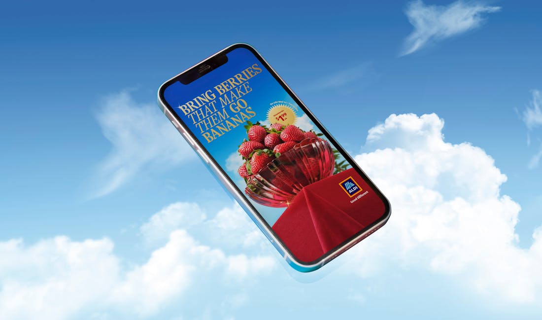 An image of an ALDI image appearing on a phone, flying through the sky. The ALDI logo and the words "Bring berries that make them go bananas" are overlaid on the image. 