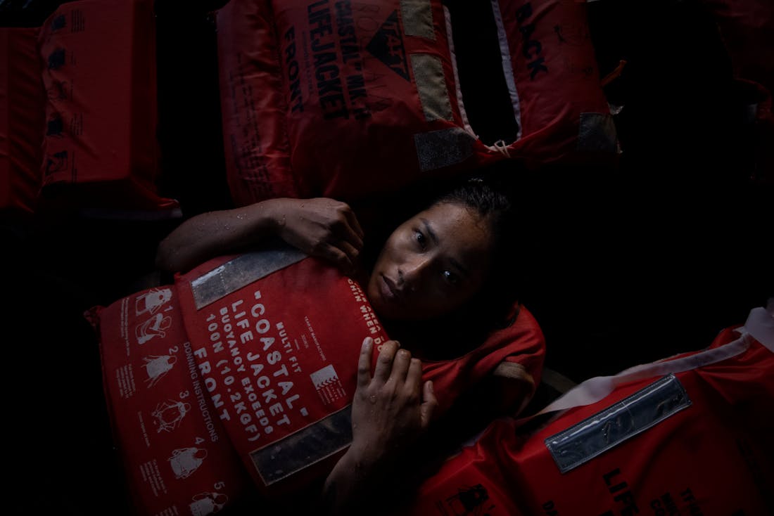 An image of a young person in a red life jacket floating on their back.