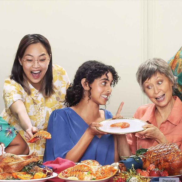 An image showing two women sitting at a dining table, they are fighting over the last prawn on a dinner plate.