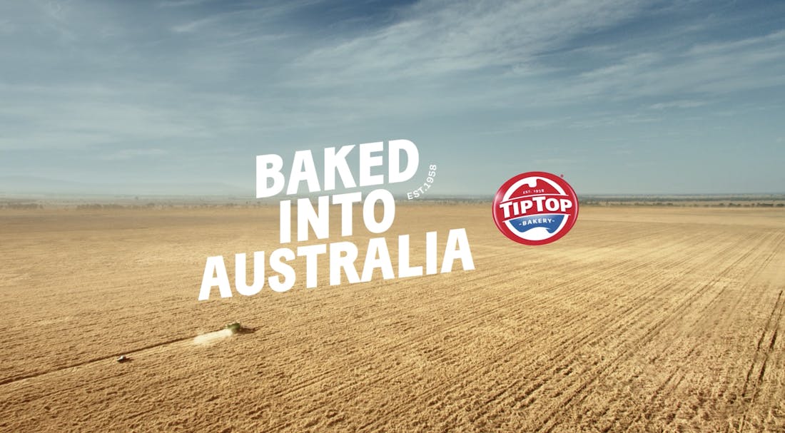 A Tip Top bakery advertisement showcasing an image of a large grain field with a harvester taken from the sky. There is a headline that reads: "Baked into Australia".