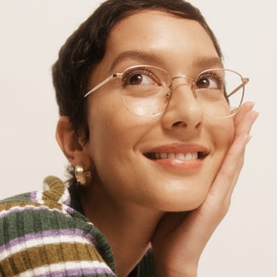 A woman wearing round metal frame gold Bailey Nelson glasses.