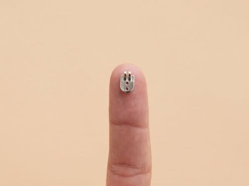 A finger holding up a metal glasses hinge