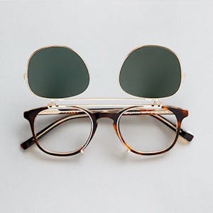 A pair of brown tort Bailey Nelson glasses with metal flip clip on sunglasses attached to the lenses