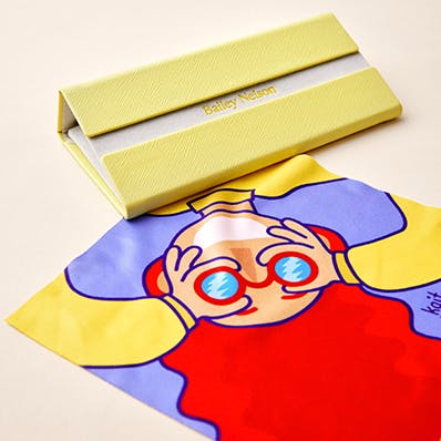 A illustrated design of a child with red hair and glasses on a lens cloth.