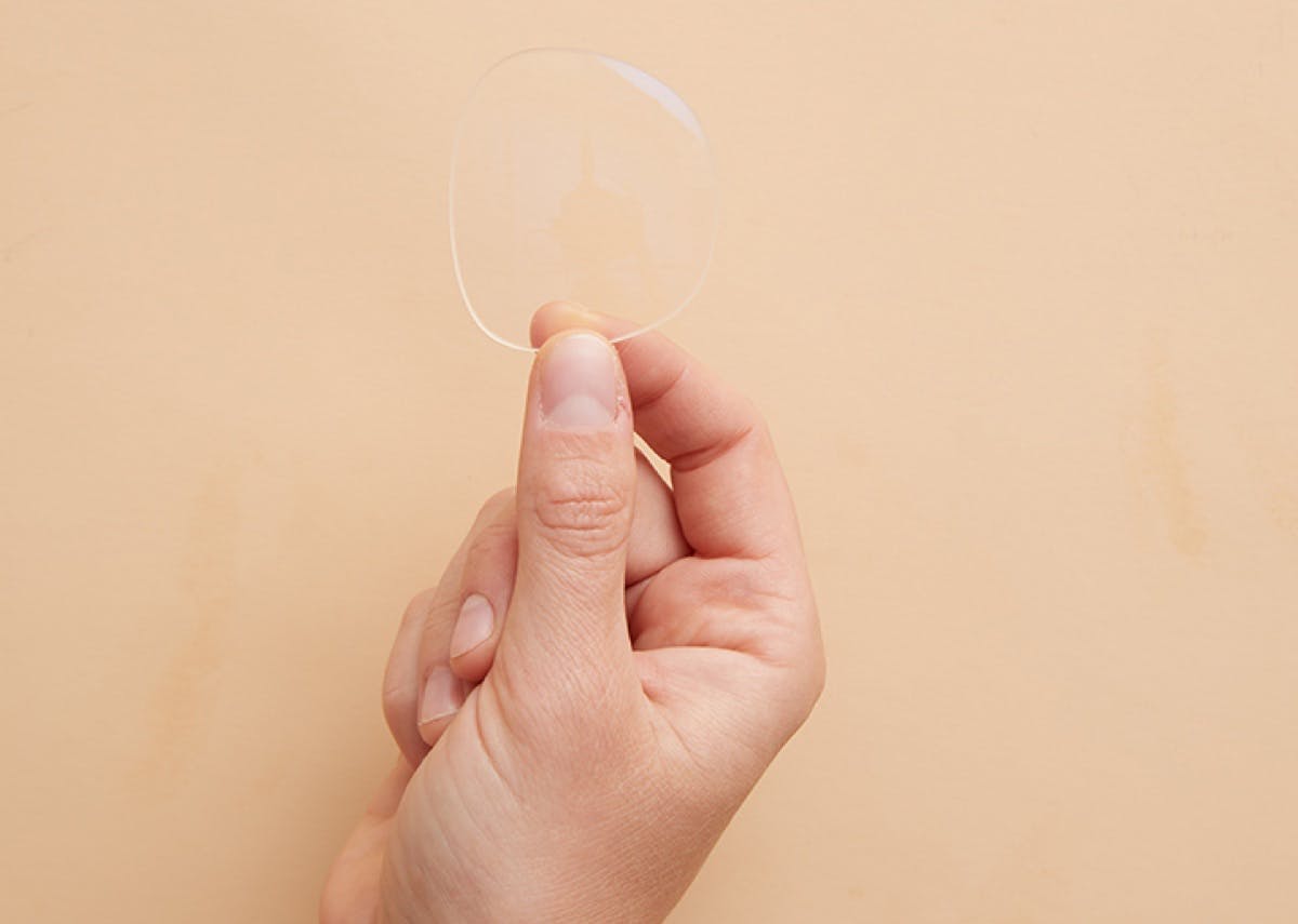 A hand holding up a lens