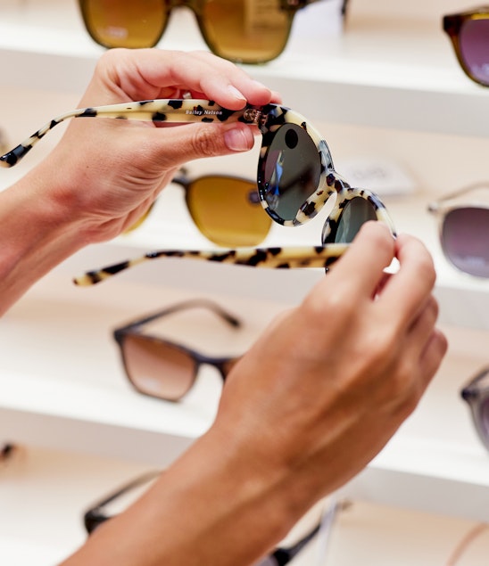 A person picks up a pair of Bailey Nelson sunglasses