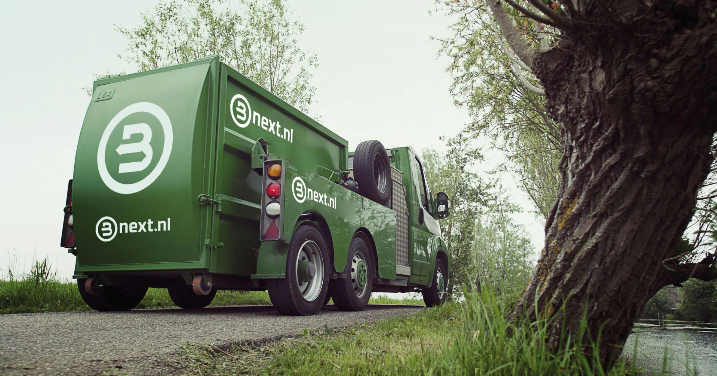 Afval ophaal wagen met nieuwe logo van Bnext.nl erop in landelijke omgeving