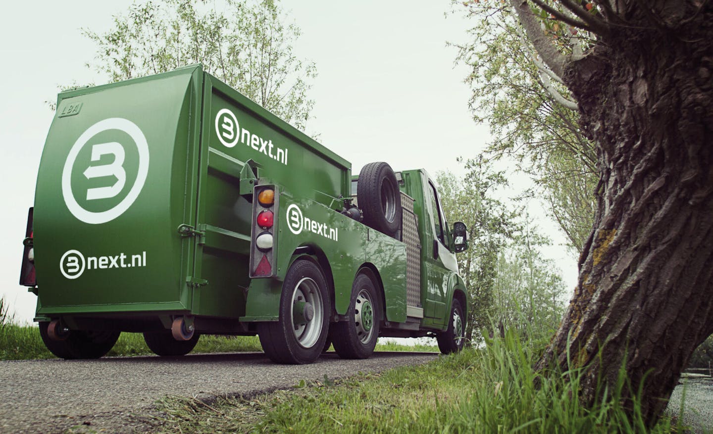 Afval ophaal wagen met nieuwe logo van Bnext.nl erop in landelijke omgeving