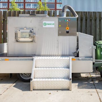 De composteermachine die op het terrein van de Jaarbeurs in Utrecht staat met rolcontainers ernaast