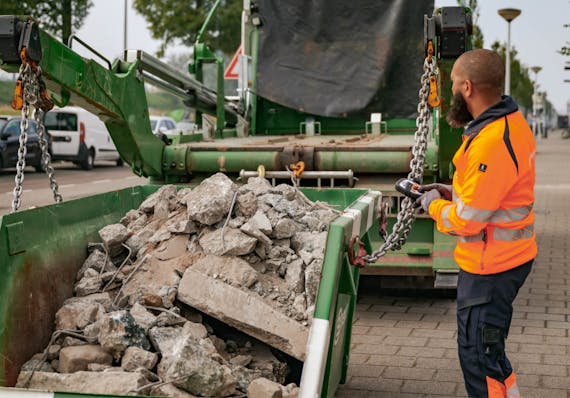 Puinafval container wordt op de wagen geladen
