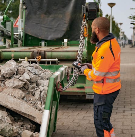 Bnext.nl medewerker laadt een afzetcontainer vol puinafval op.