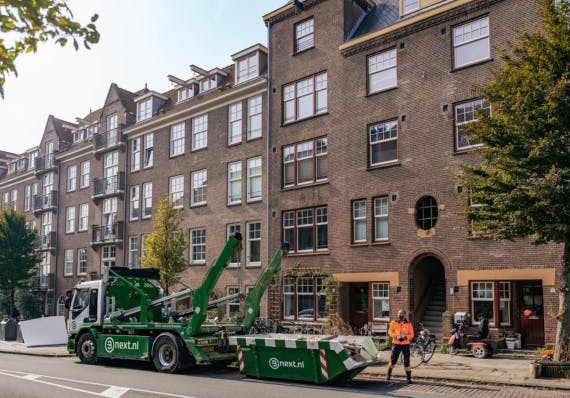 Afzetcontainer wordt opgehaald in een stadsstraat