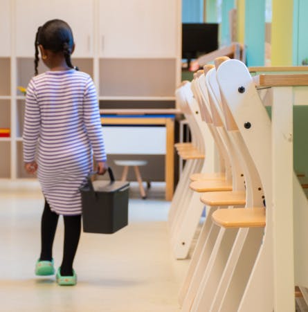 klein meisje loopt met een bonton mini door een schoolgebouw