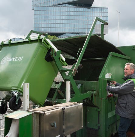 Bnext.nl medewerker leegt rolcontainer in een perscontainer