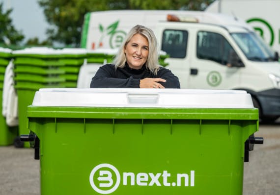 Een groene container van Bnext.nl met een vrouw die erop leunt.