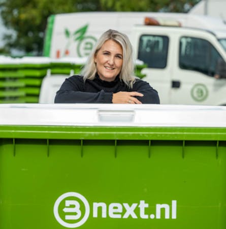Een groene container van Bnext.nl met een vrouw die erop leunt.