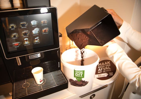 Koffiedroes wordt naast een koffie automaat in een Bnext.nl emmer gedaan. 