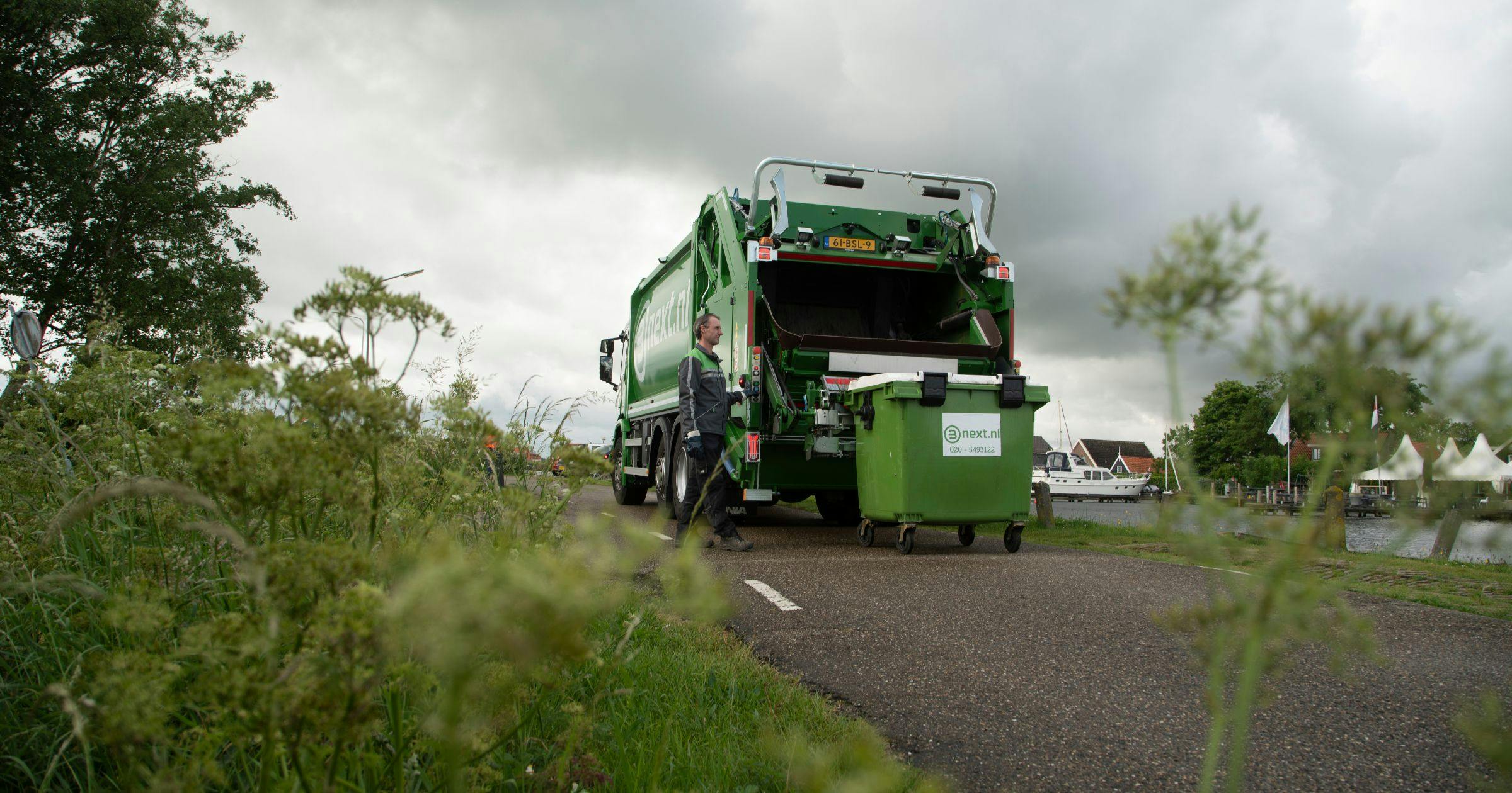 afvalcontainer wordt opgehaald in landelijke omgeving