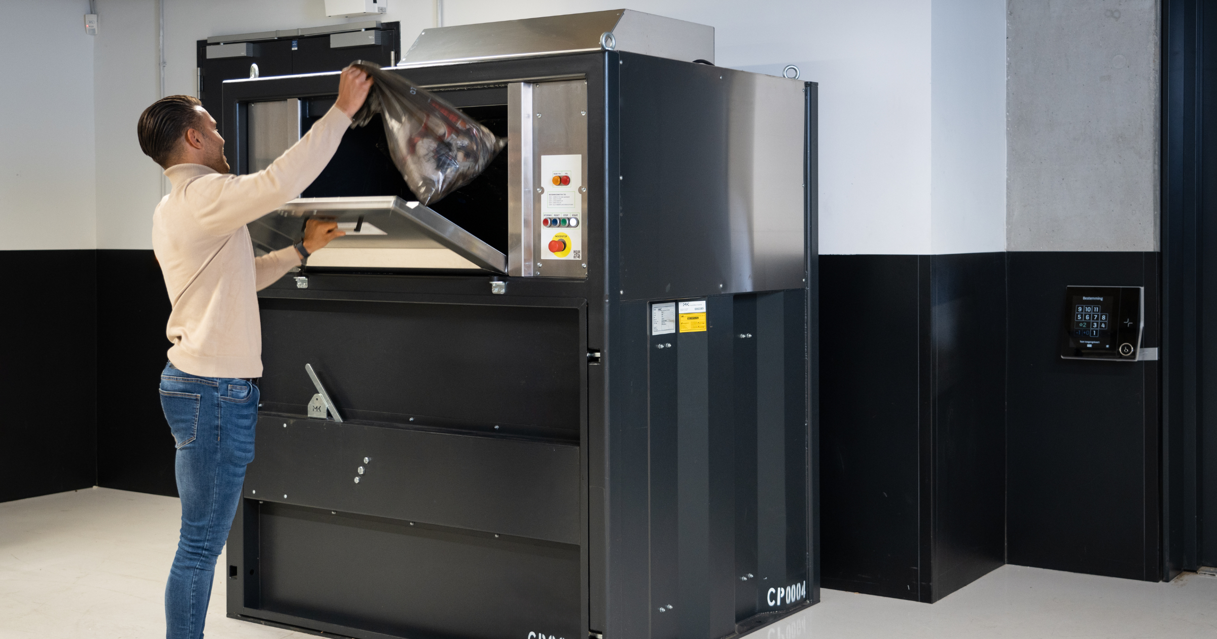 Man gooit afval in de perscontainer in de kelder van een kantoorgebouw