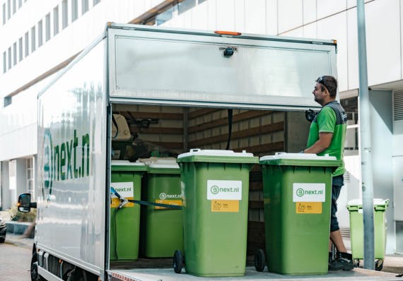Rolcontainers worden in de laadklep van de vrachtwagen gezet.