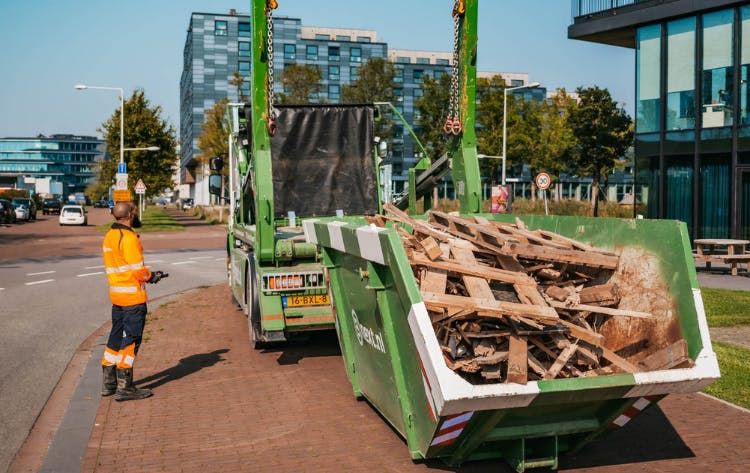 houtafval in een container wordt op een wagen geladen