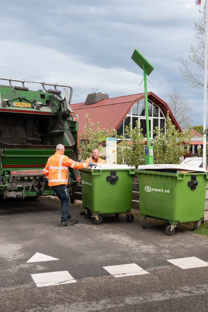 Vrachtwagenchauffeurs ledigen een rolcontainer bij een horeca klant