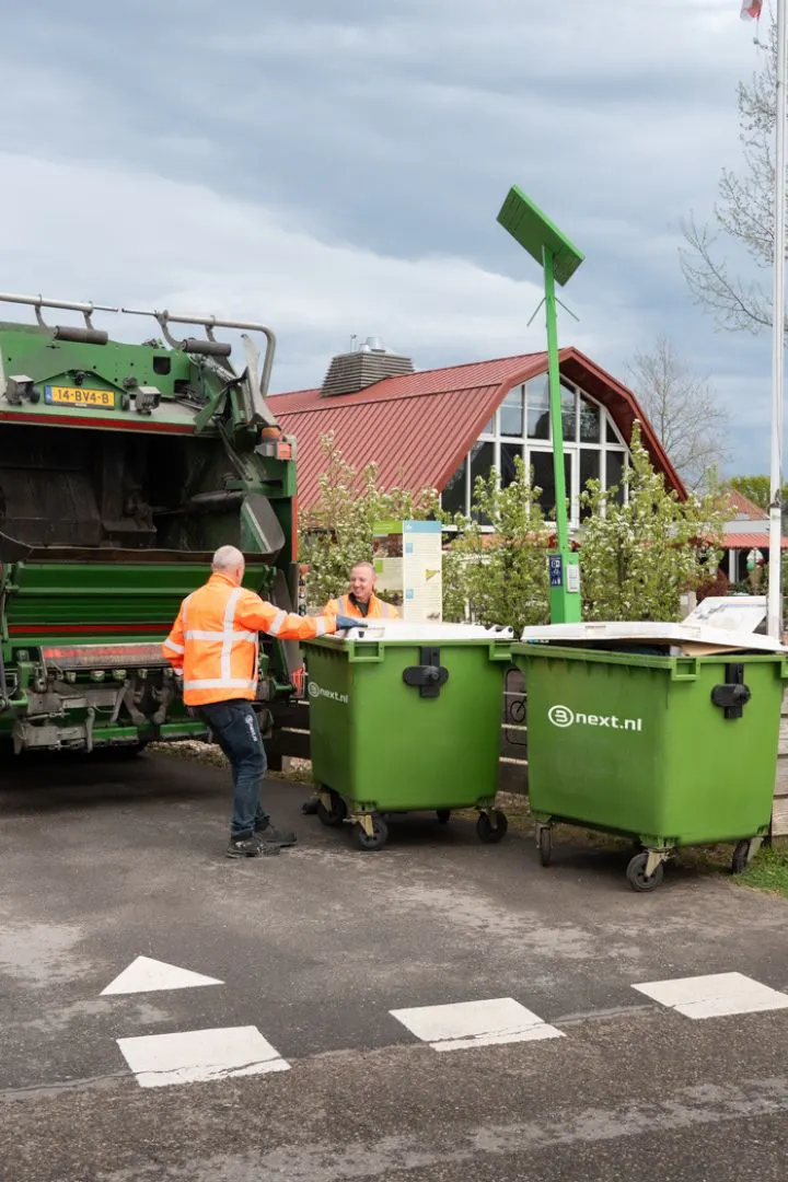 Vrachtwagenchauffeurs ledigen een rolcontainer bij een horeca klant
