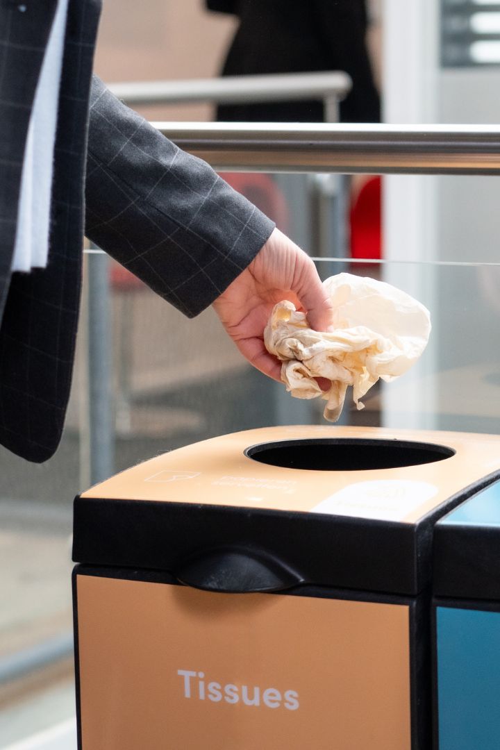 Iemand die een tissue in een prullenbak gooit