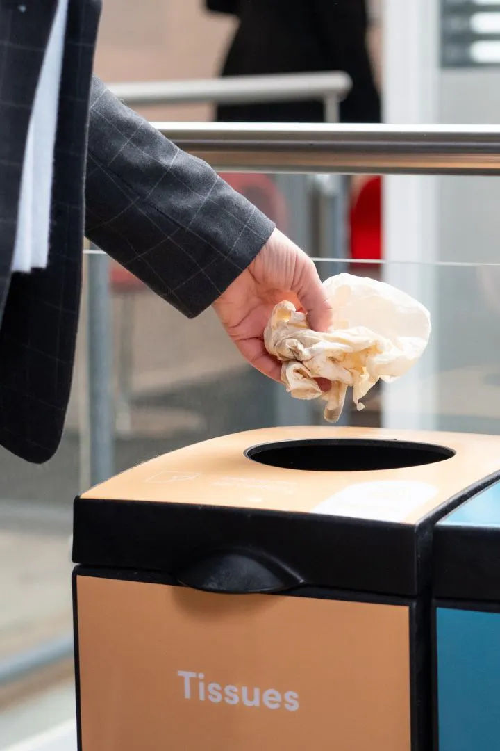 Iemand die een tissue in een prullenbak gooit