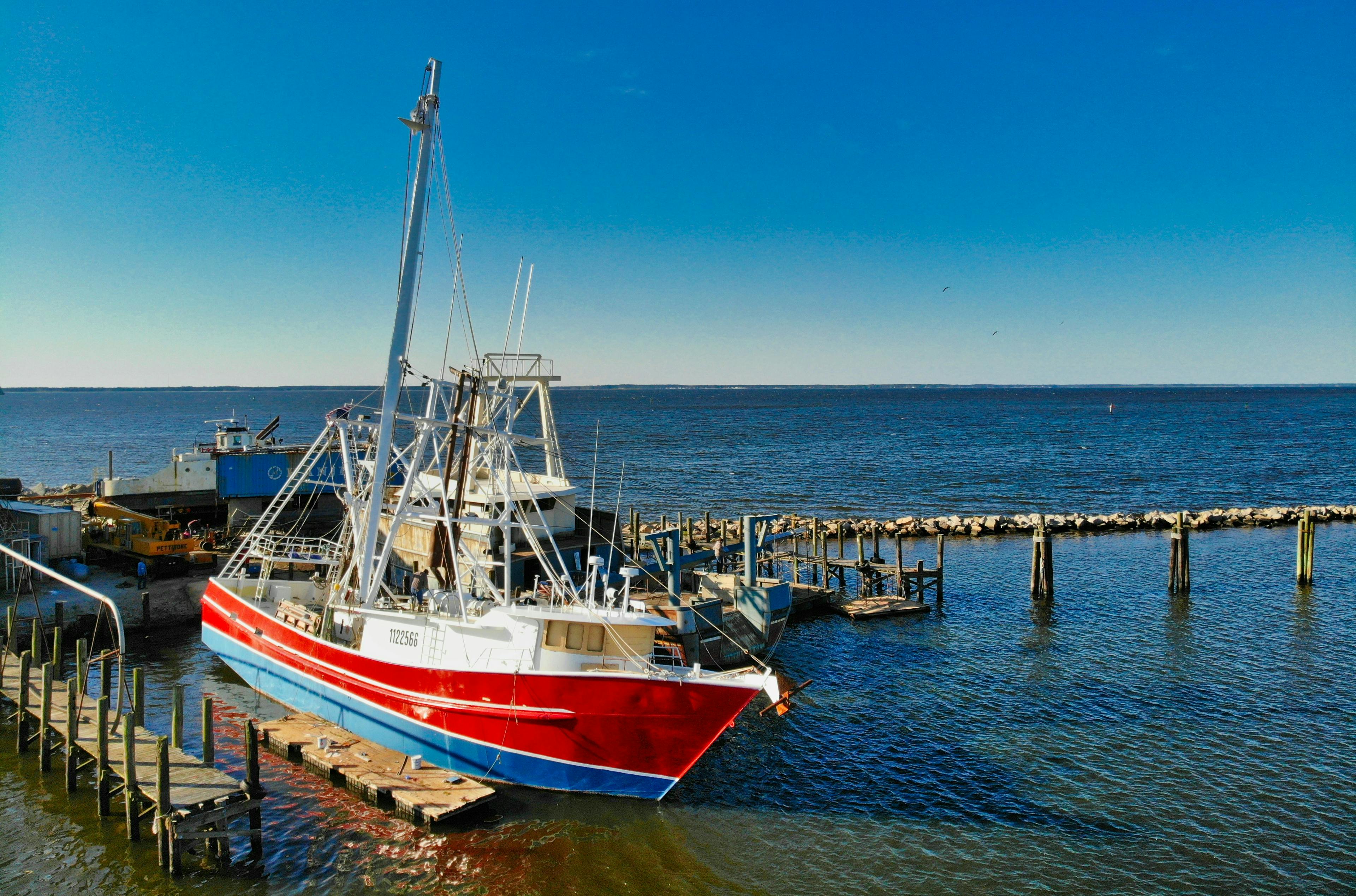 red-blue boat is docked next to the dock in the sea. Cost Considerations for Buying a Boat: What You Need to Know