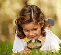 little girl looking through a magnifying glass