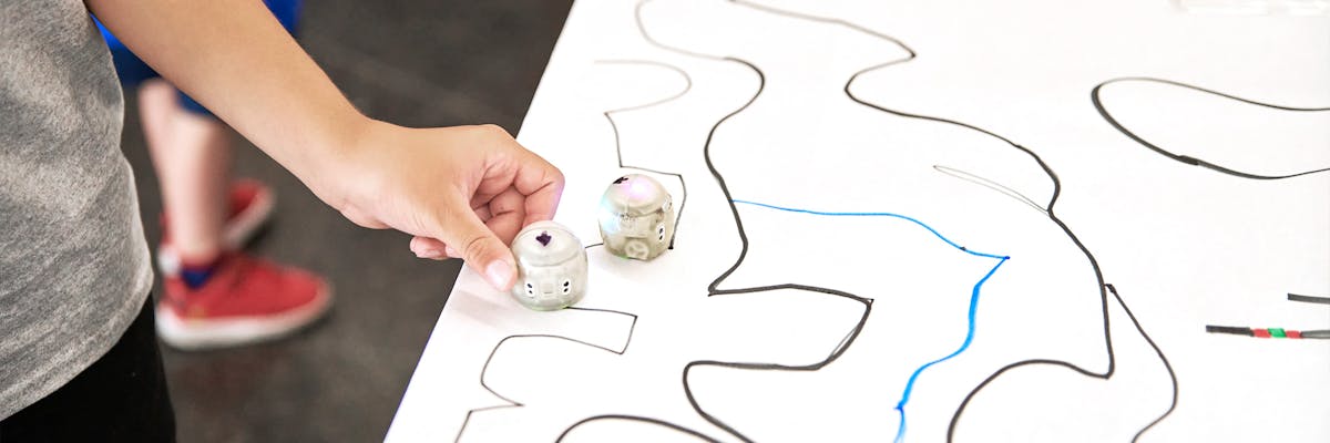 A child explores the robotics table with an Ozobot.