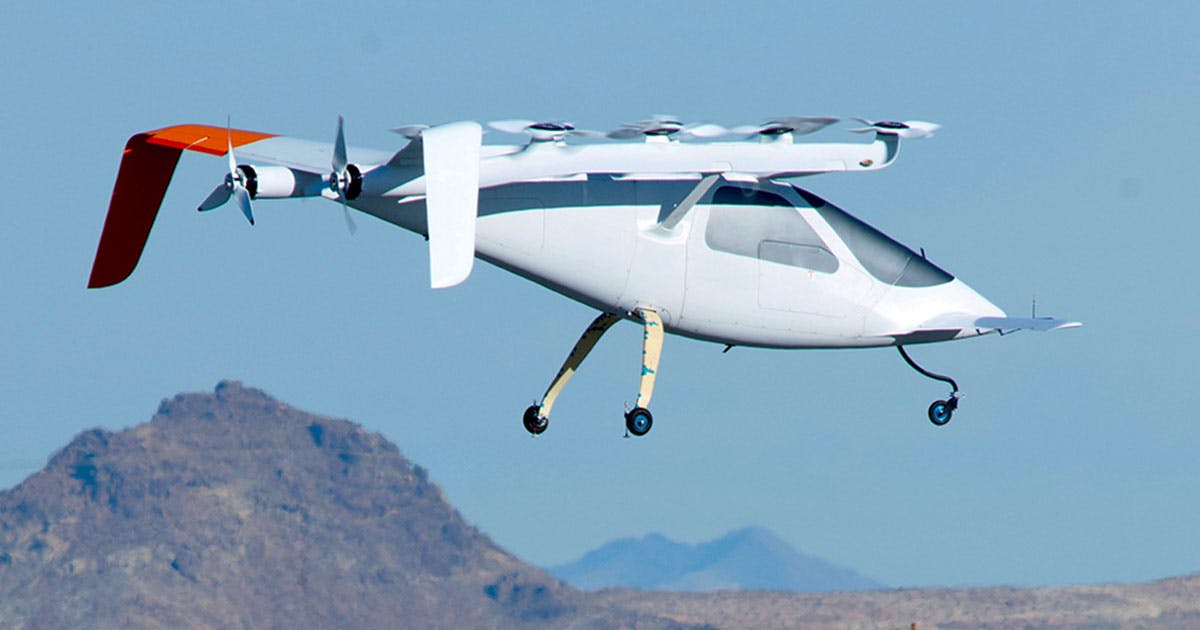 Wisk Aero Gen 1 in vertical takeoff, with clear skies and mountain peaks in the background.