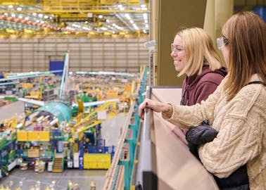 Tour guests overlook the balcony from inside the Boeing Everett Factory. The Boeing 777 assembly line is in motion on the factory floor below.