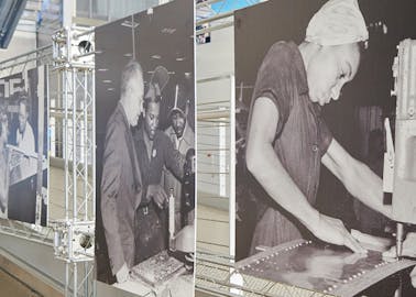 Scaffolding with large, black-and-white images of our 'Rosie's' hard-at-work in the Boeing factory, building airplane parts.