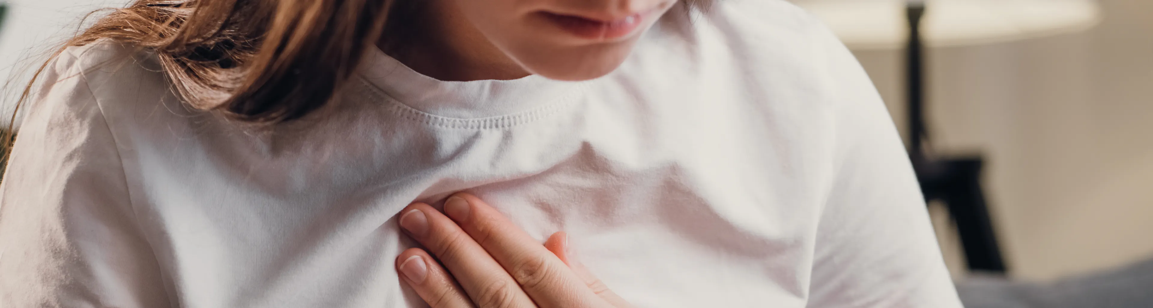 donna con maglietta bianca si tiene il petto durante una crisi d’asma