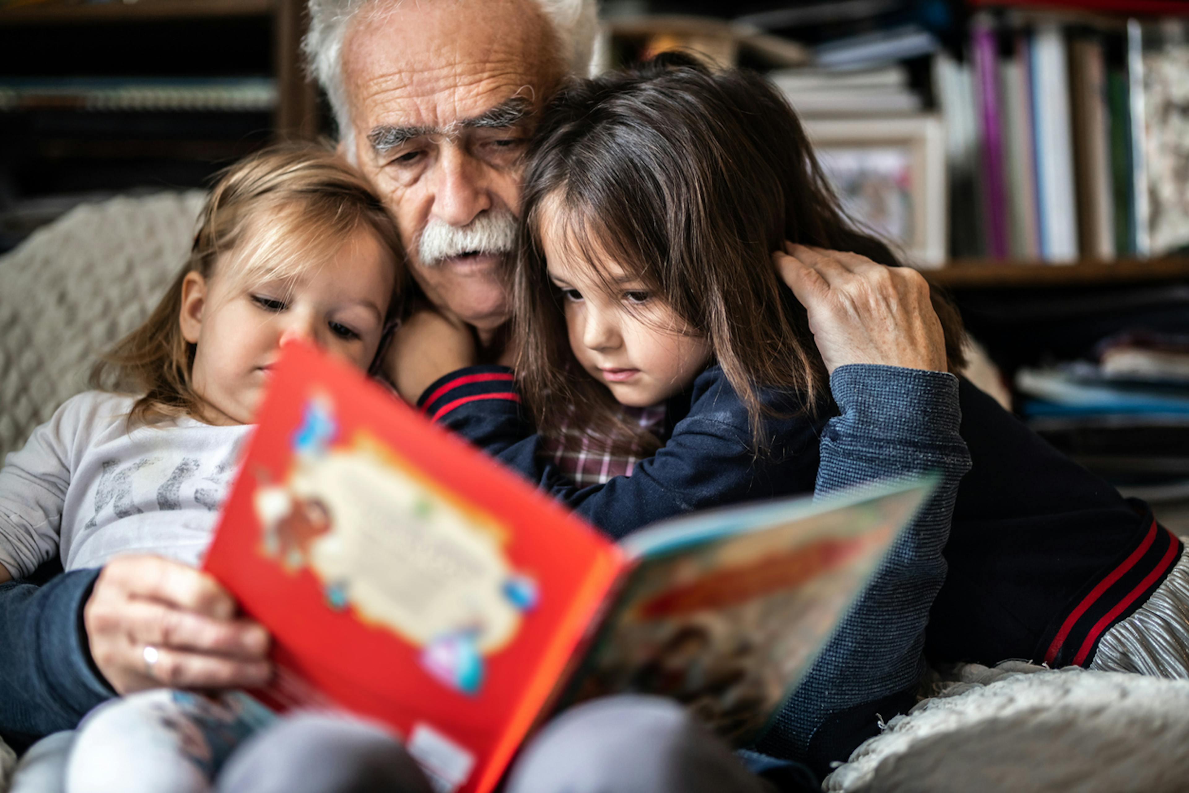 nonno che legge libro a nipotine malate