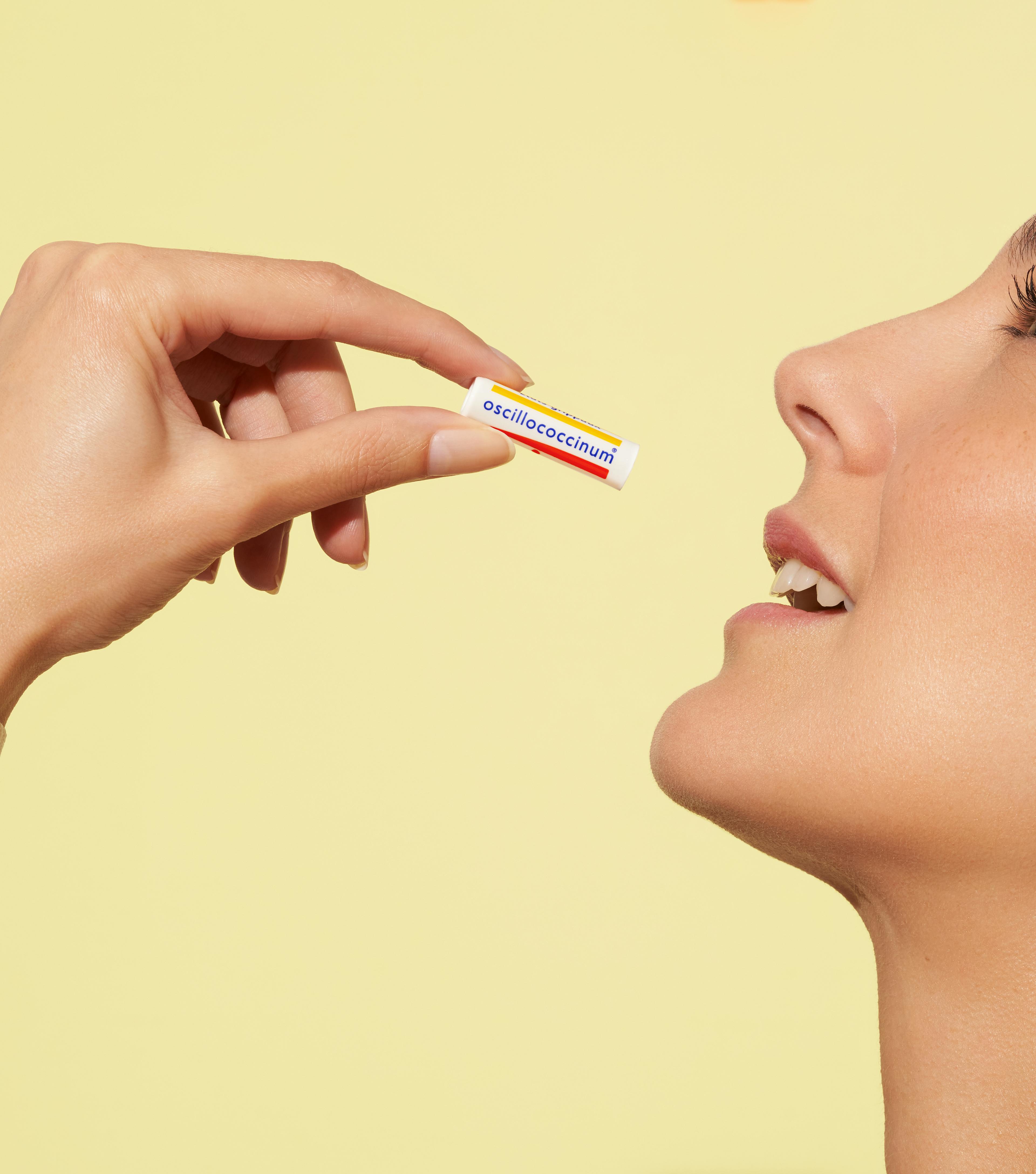 main et visage prenant une dose d'oscillococcinum
