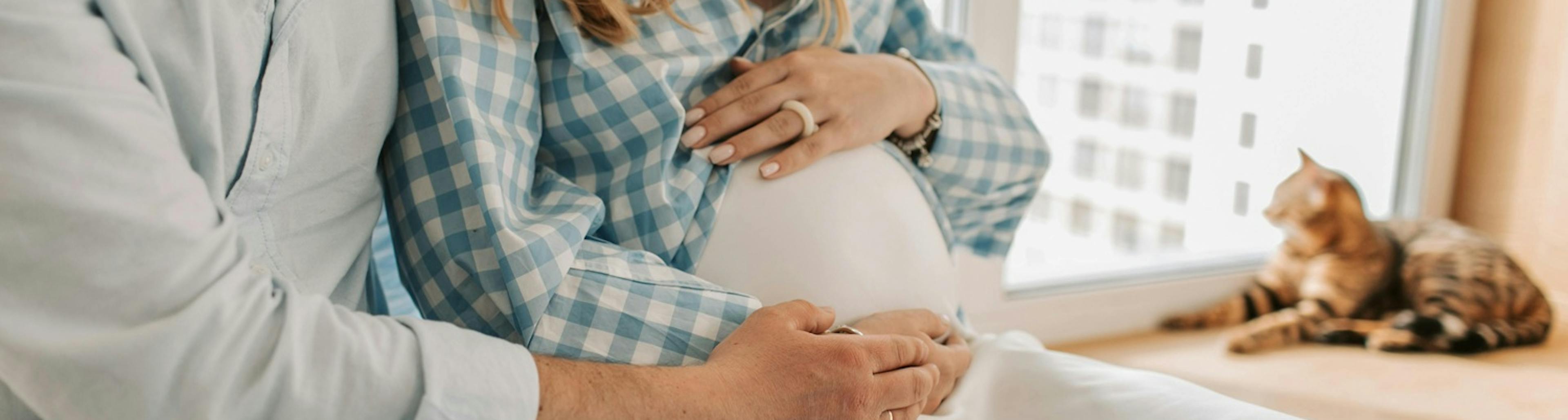 těhotná žena sedí s mužem, objímají bříško