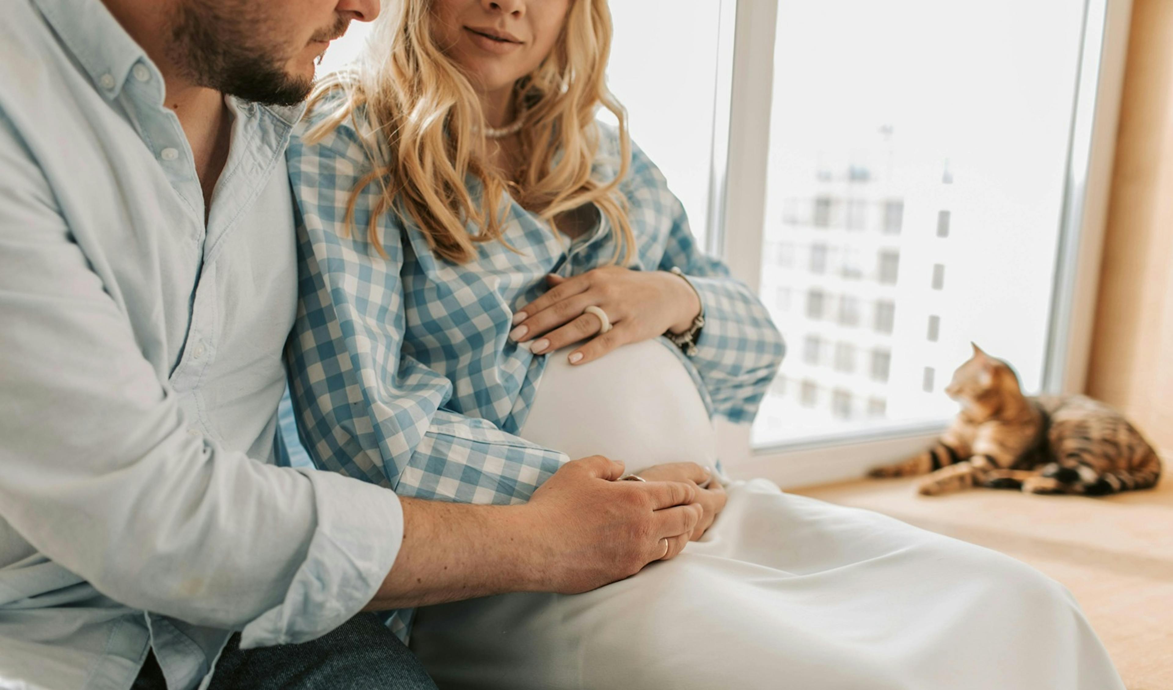 těhotná žena sedí s mužem, objímají bříško