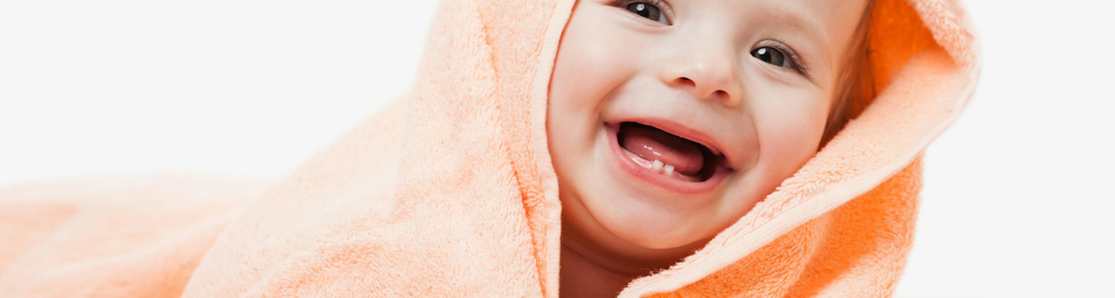 Neonato avvolto in un asciugamano a cui stanno spuntando molari e canini