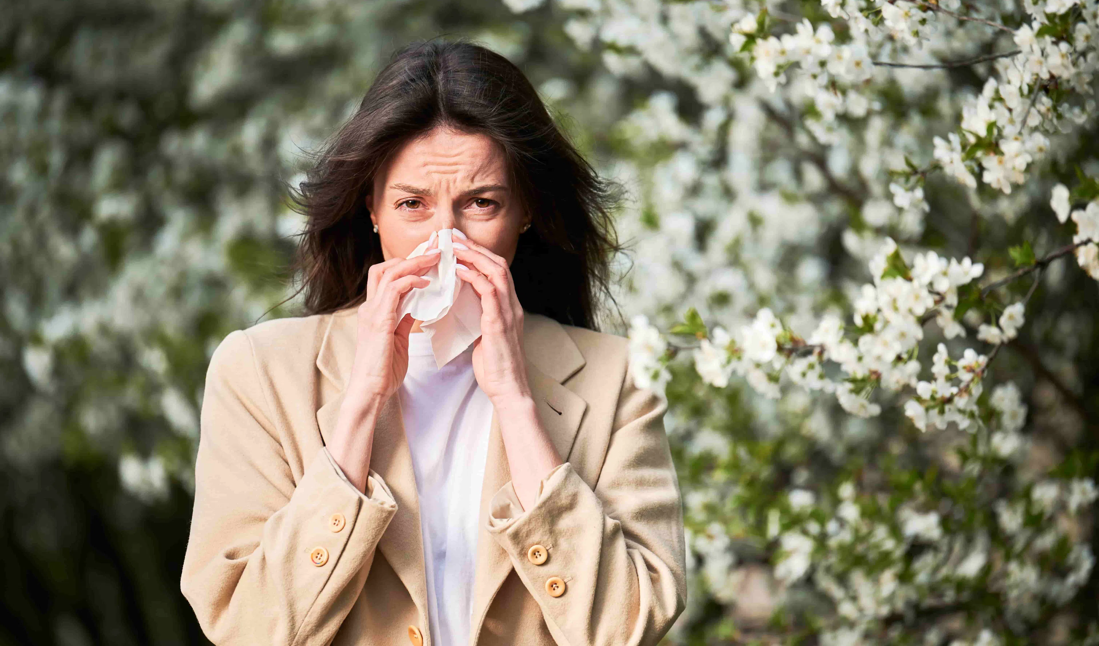 Femme éternuant à l'extérieur à cause du pollen printanier 