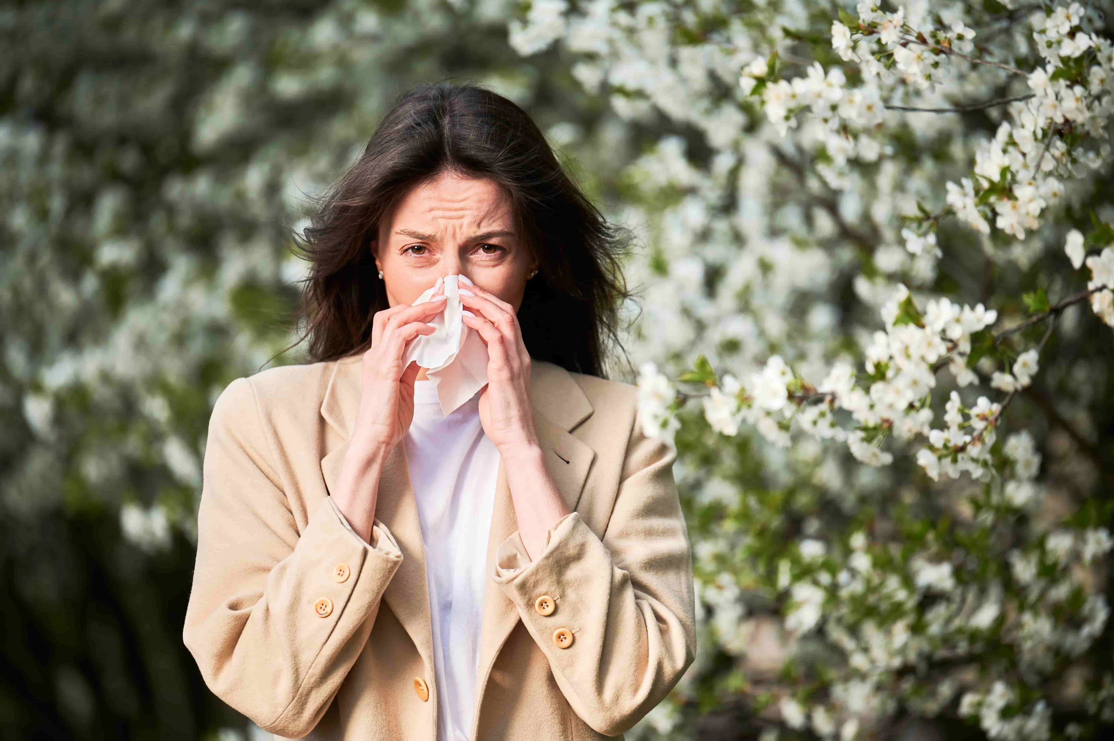 Femme éternuant à l'extérieur à cause du pollen printanier 