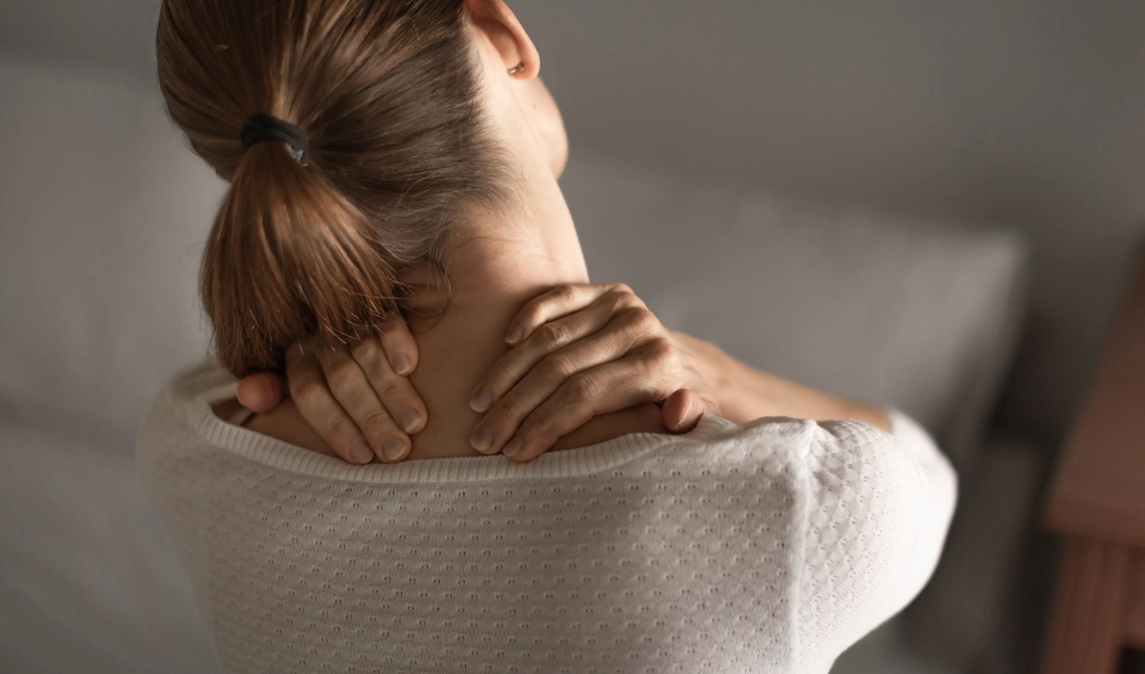 Donna che si massaggia il collo per via di una tensione muscolare