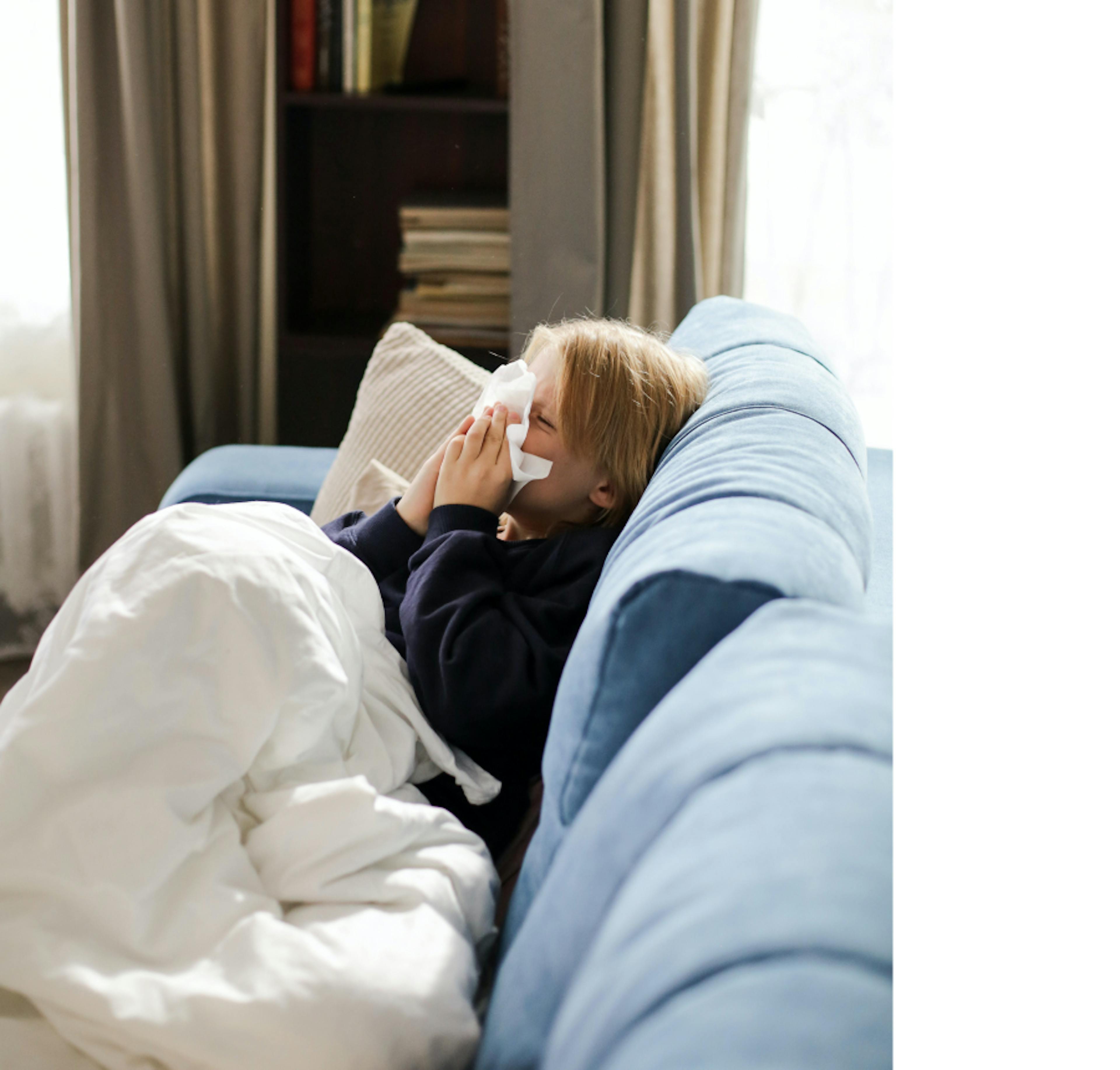 Imagen de un niño en el sofá de su casa con síntomas de gripe