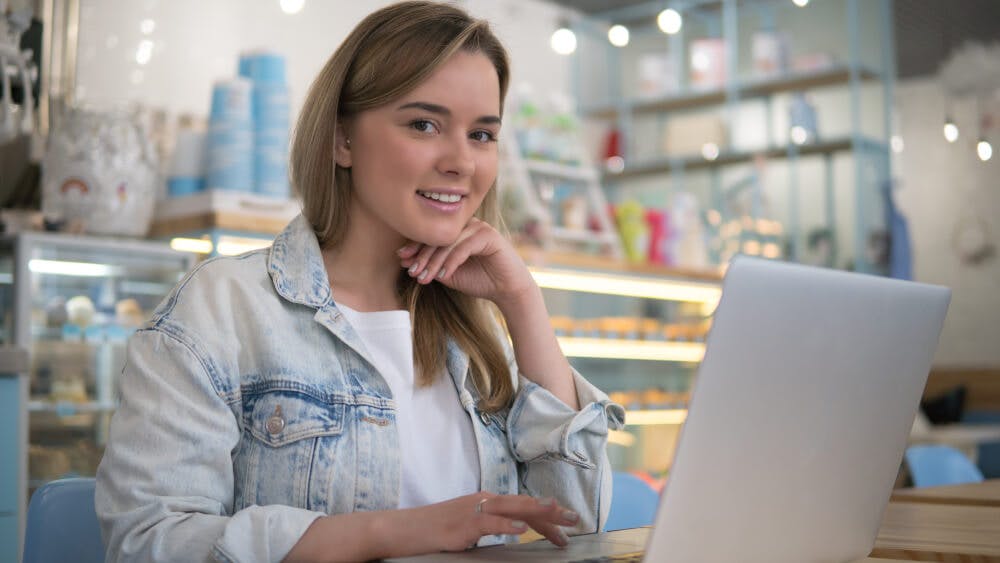 smiling young woman using laptop in bakery